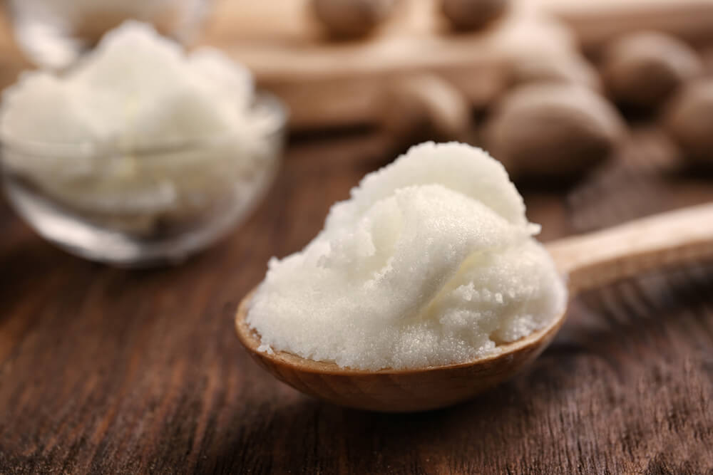 spoon of shea butter in front of shea nuts